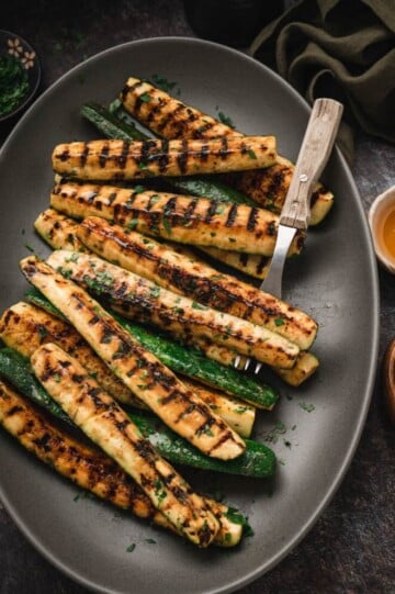 Grilled zucchini on a black plate.