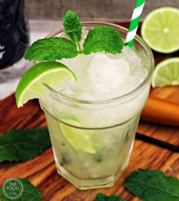 Light green drink with ice, lime and mint, green and white striped straw.