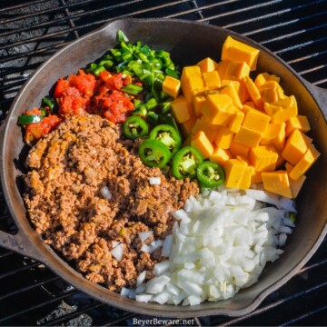 Velveeta cheese, white onion, crumbled sausage, tomatoes and green pepper in a cast iron skillet on the grill.