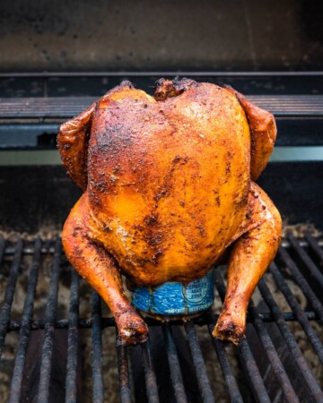 Whole smoked chicken standing up on a beer can.