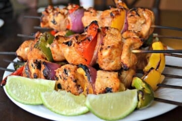 Chicken kabobs with lime wedges.