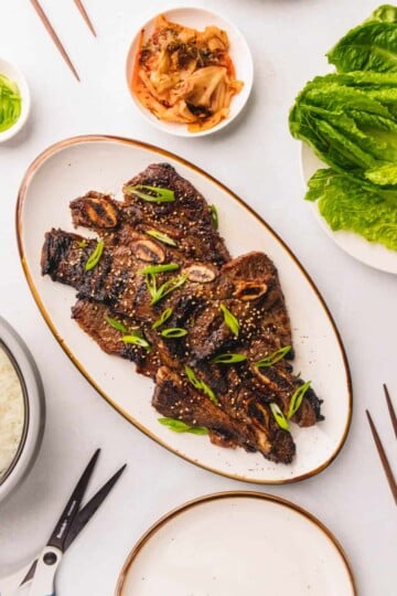 Marinated flank short ribs on a gold rimmed white plate.