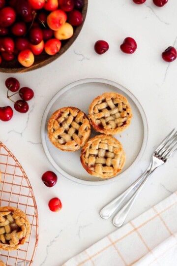 Cherry hand pies on a plate next to a bowl of cherries.
