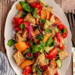 Red and yellow tomatoes in a salad with bread and cucumbers.