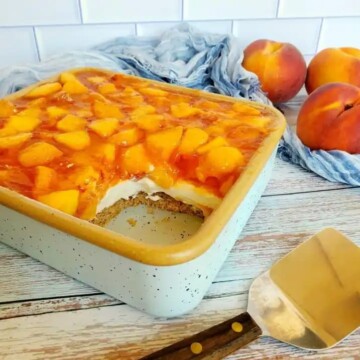Yellow rimmed specked baking dish with peach covered cheesecake with slice missing.