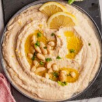 A bowl of bean dip topped with olive oil and lemon slices.