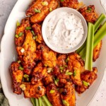 Chicken wings with ranch dressing and celery sticks.