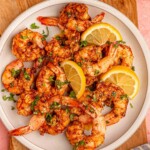 Shrimp on a plate with lemon wedges.