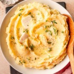 Mashed potatoes topped with butter slices and fresh thyme.