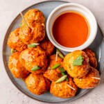 Buffalo chicken meatballs on a plate topped with scallions.