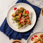 A white plate on a blue napkin full of rice and chicken stir fry.