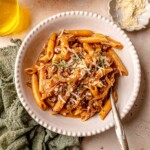A bowl of penne pasts with onions, beef and thyme.