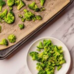 Broccoli on a sheet pan with parchment paper and on a white plate.