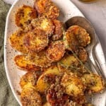 Crispy roasted potatoes on a white platter with thyme garnish.