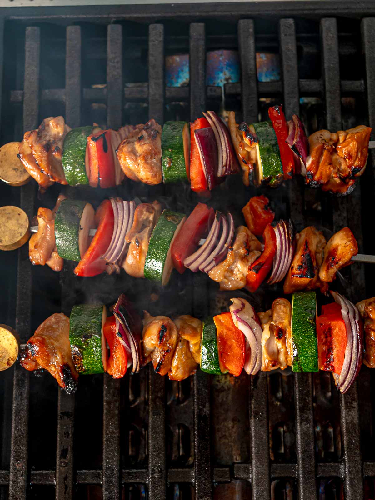 Skewers of chicken and veggies starting to char on the grill.