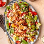 Platter of grilled chicken Cobb salad with avocado, hard-boiled eggs, tomatoes, bacon, feta, and romaine.