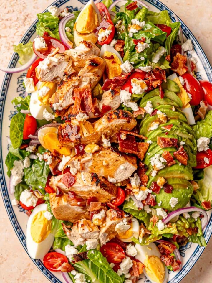 Sliced grilled chicken atop Cobb salad with avocado and crumbled feta.