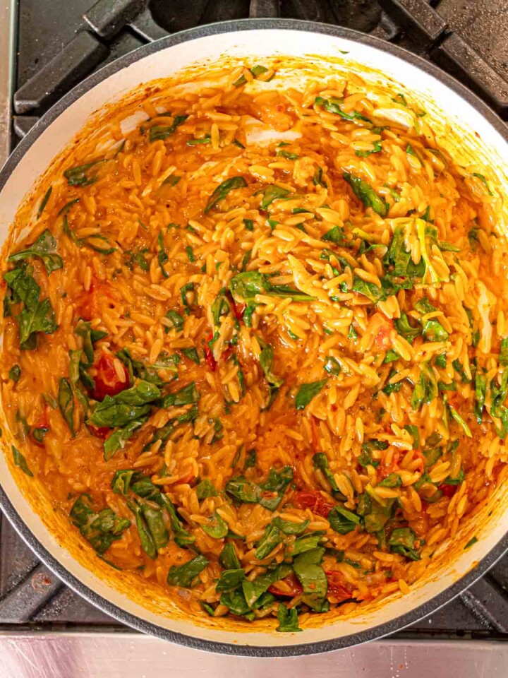 Finished creamy tomato orzo mixed with spinach in a pot.