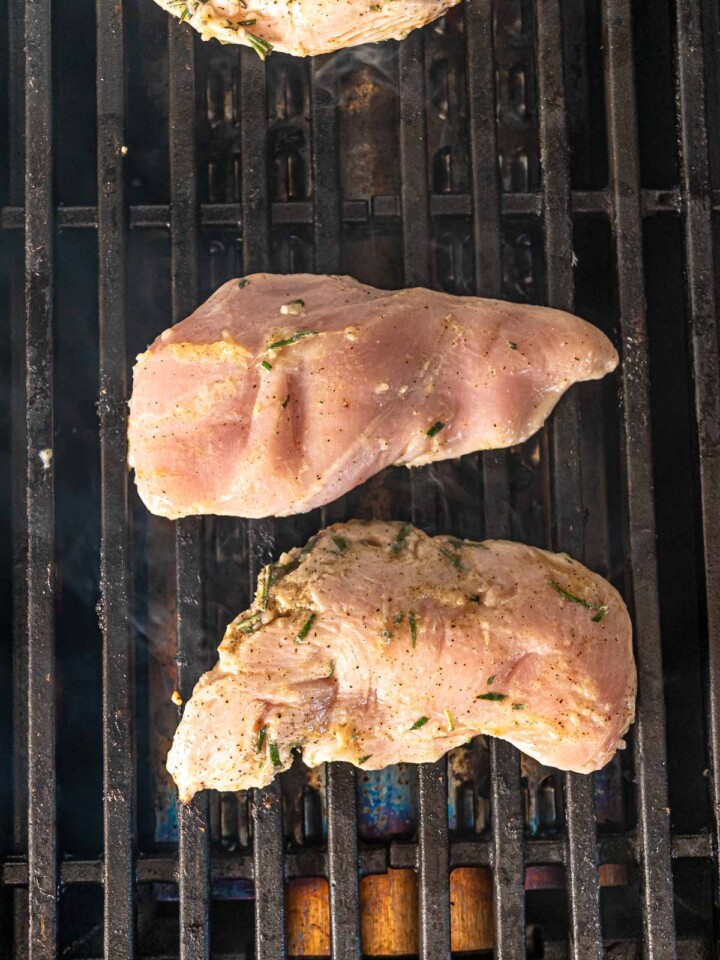 Raw, marinated chicken breasts placed on a grill.