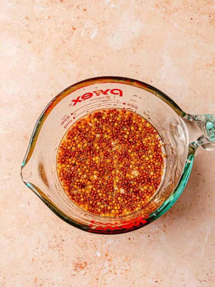 Honey mustard marinade made with whole grain mustard and olive oil in a measuring cup.