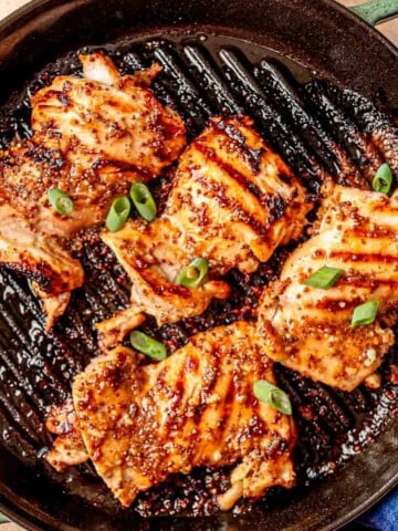 Golden brown grilled chicken thighs with honey mustard marinade on a grill pan.