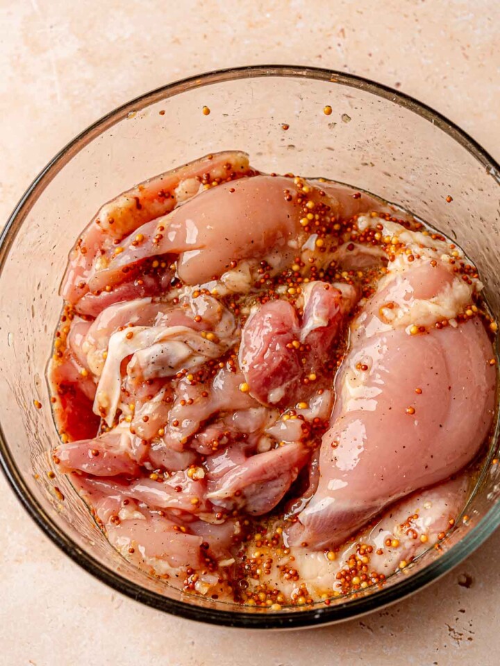 Raw chicken thighs marinating in a honey mustard garlic mixture.