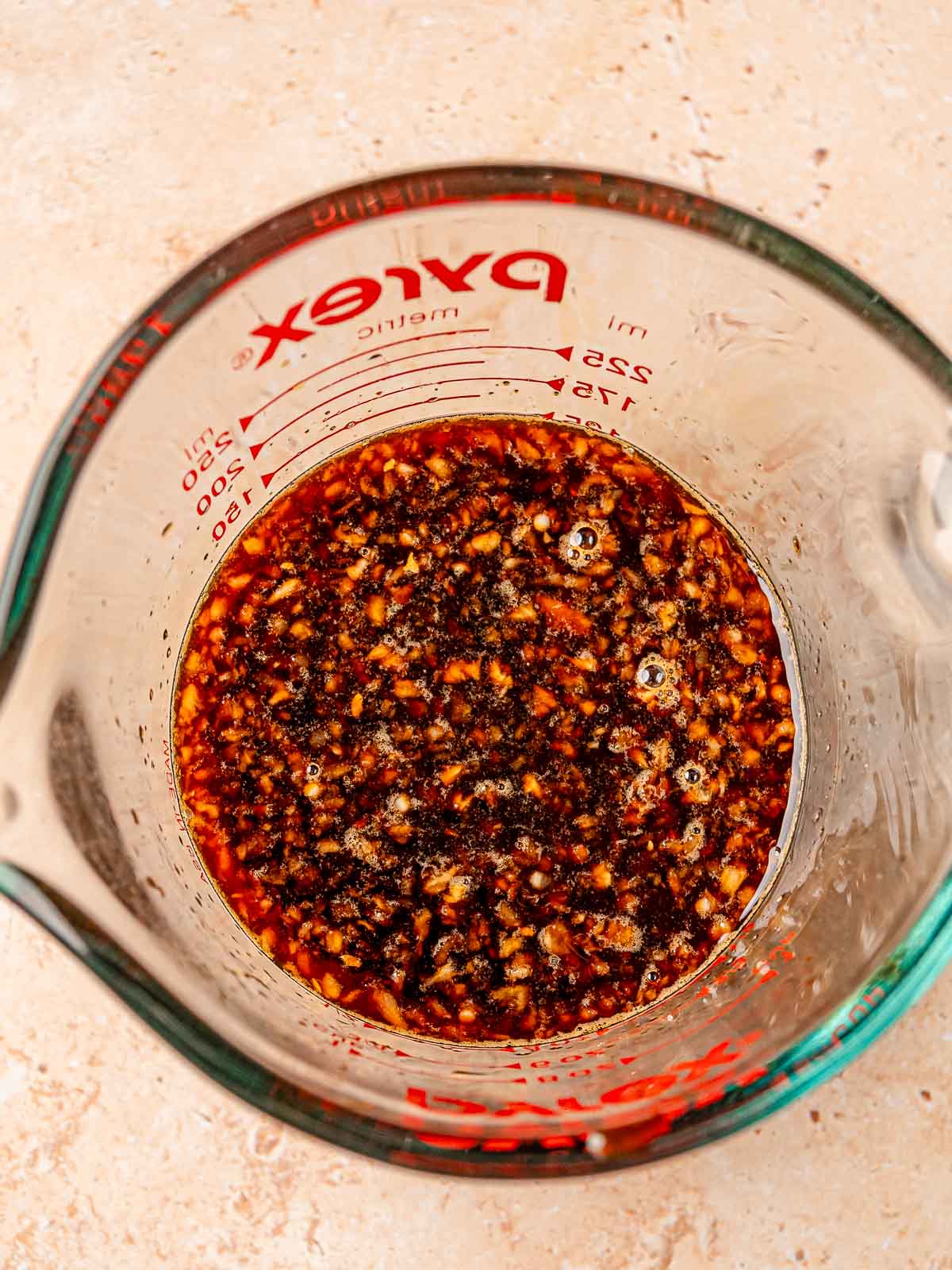 Teriyaki sauce mixture made with garlic, ginger, honey, and coconut aminos in a glass measuring cup.