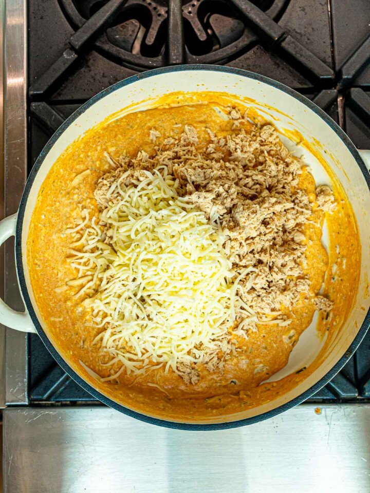 Shredded chicken and mozzarella cheese added to the buffalo sauce in a Dutch oven.