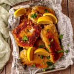 Crispy golden panko air fryer haddock fillets served in a basket with lemon wedges and parsley.
