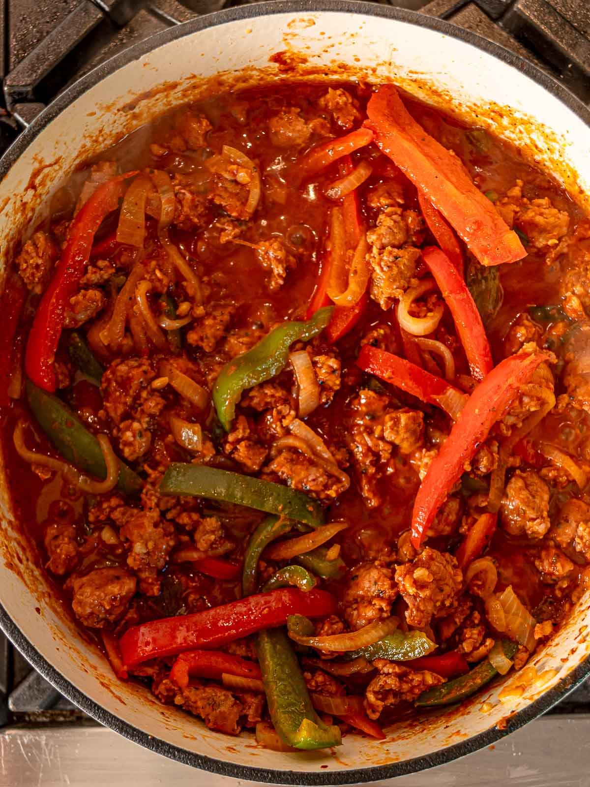 Sausage, peppers, and onions simmering in marinara sauce to create a rich pasta topping.