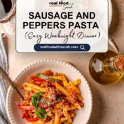 Pinterest graphic for Sausage and Peppers Pasta recipe, featuring a white bowl of penne pasta with Italian sausage, bell peppers, and marinara sauce, topped with Parmesan and basil. Includes text overlay: "Sausage and Peppers Pasta (Easy Weeknight Dinner)" and the website realfoodwithsarah.com.