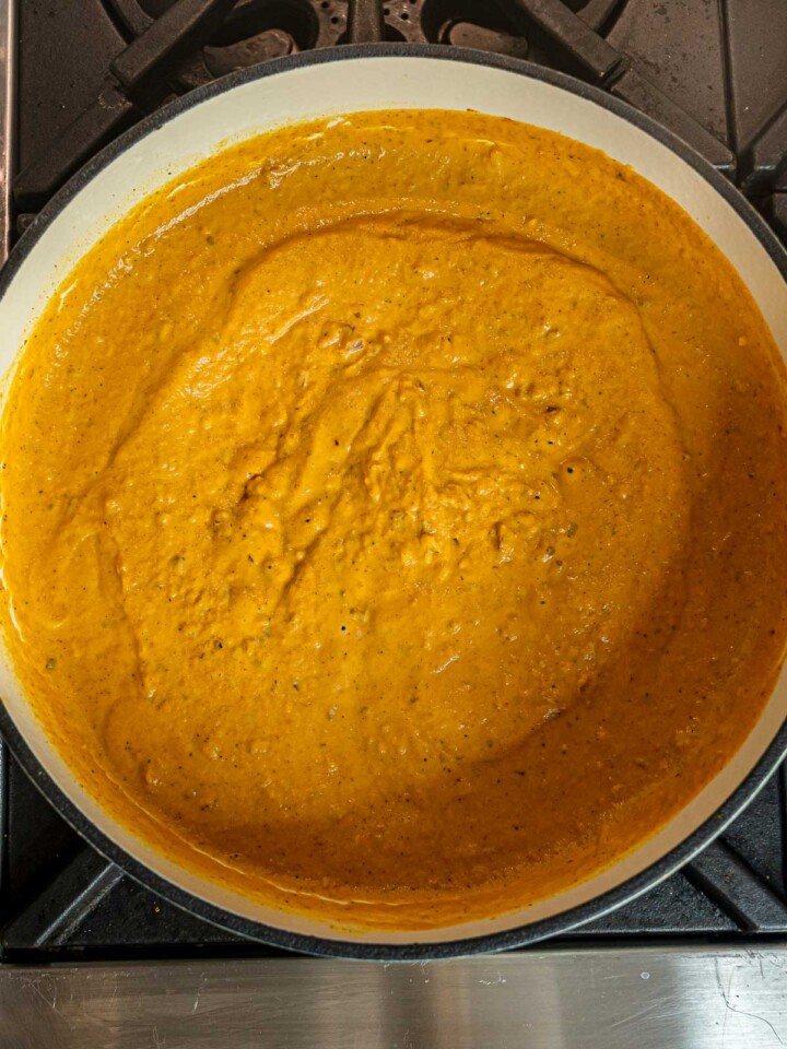 Thick pumpkin pasta sauce simmering until smooth and velvety in a Dutch oven.