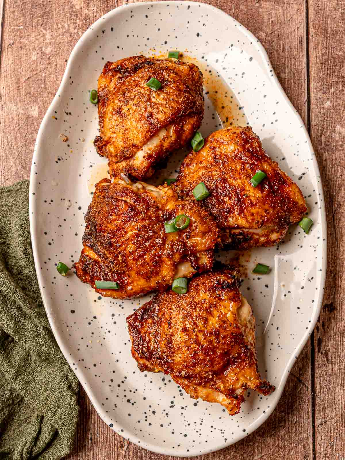 Air-fried chicken thighs, skin perfectly crisp with a glistening finish, garnished with scallions.