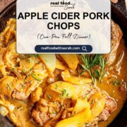 Cooked pork chops nestled in a skillet with caramelized apples, onions, cider sauce, and fresh rosemary pin.