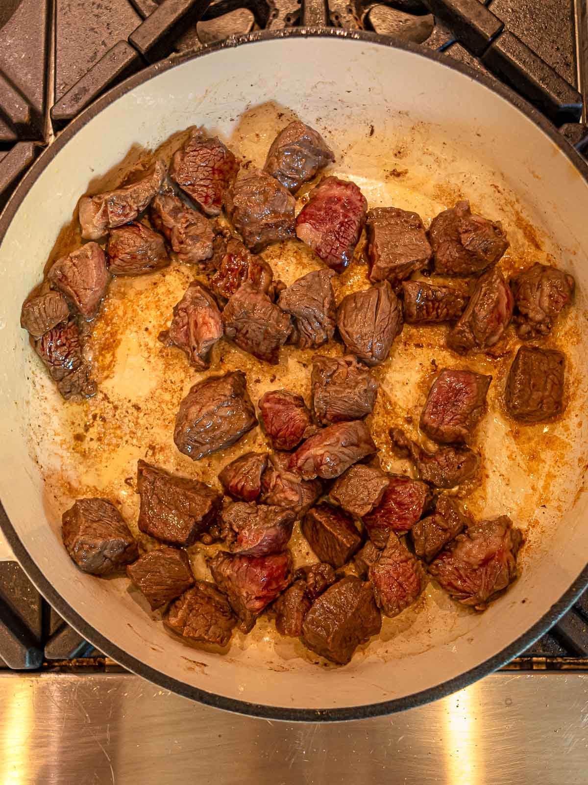 Chunks of stew beef searing in a Dutch oven until browned for added flavor.
