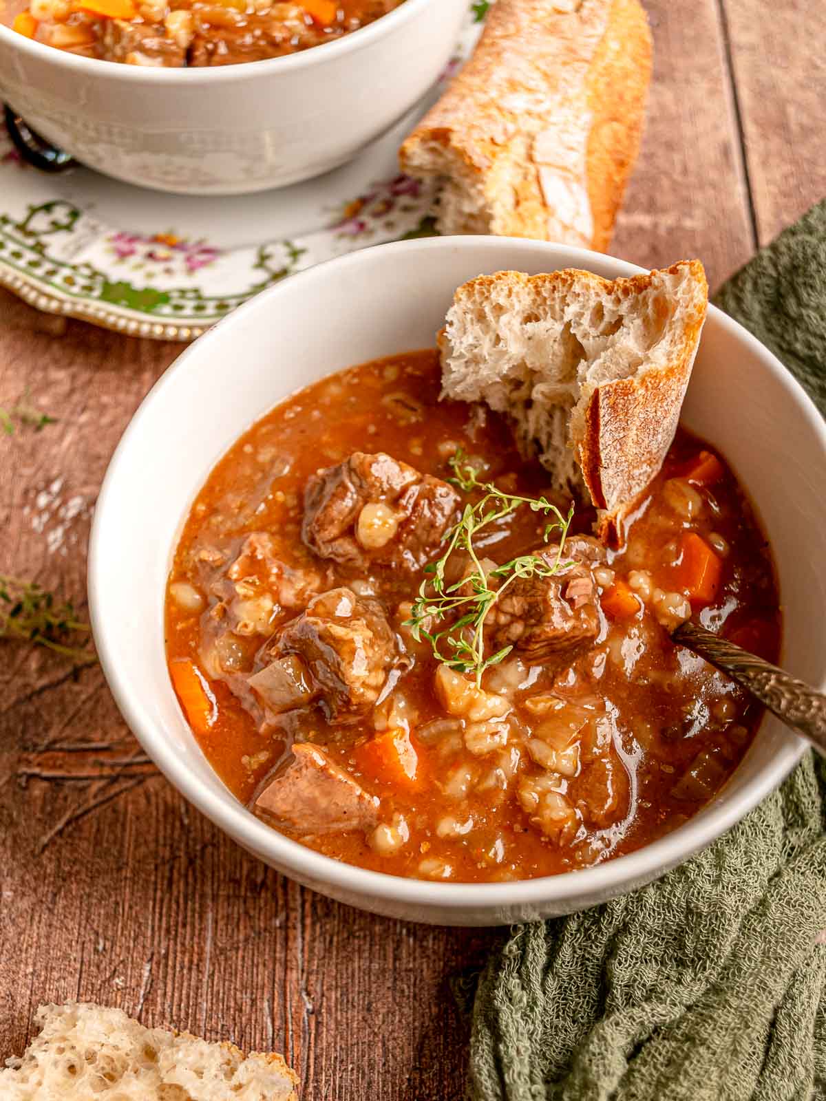 Hearty beef and barley soup in a white bowl with carrots, celery, and tender beef.