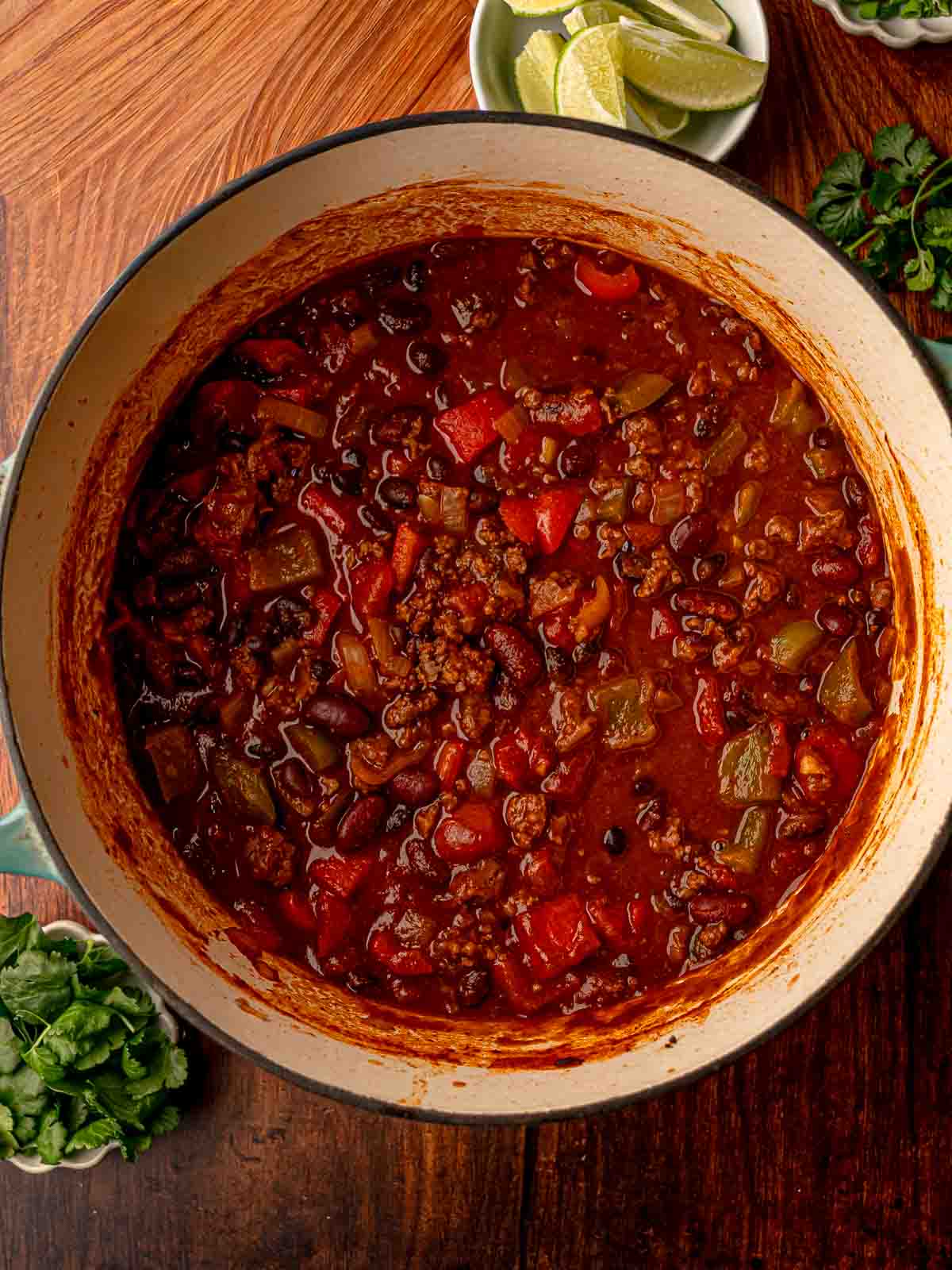 Thickened beef chili with beans and vegetables simmering, edges of the pot showing a rich tomato base.