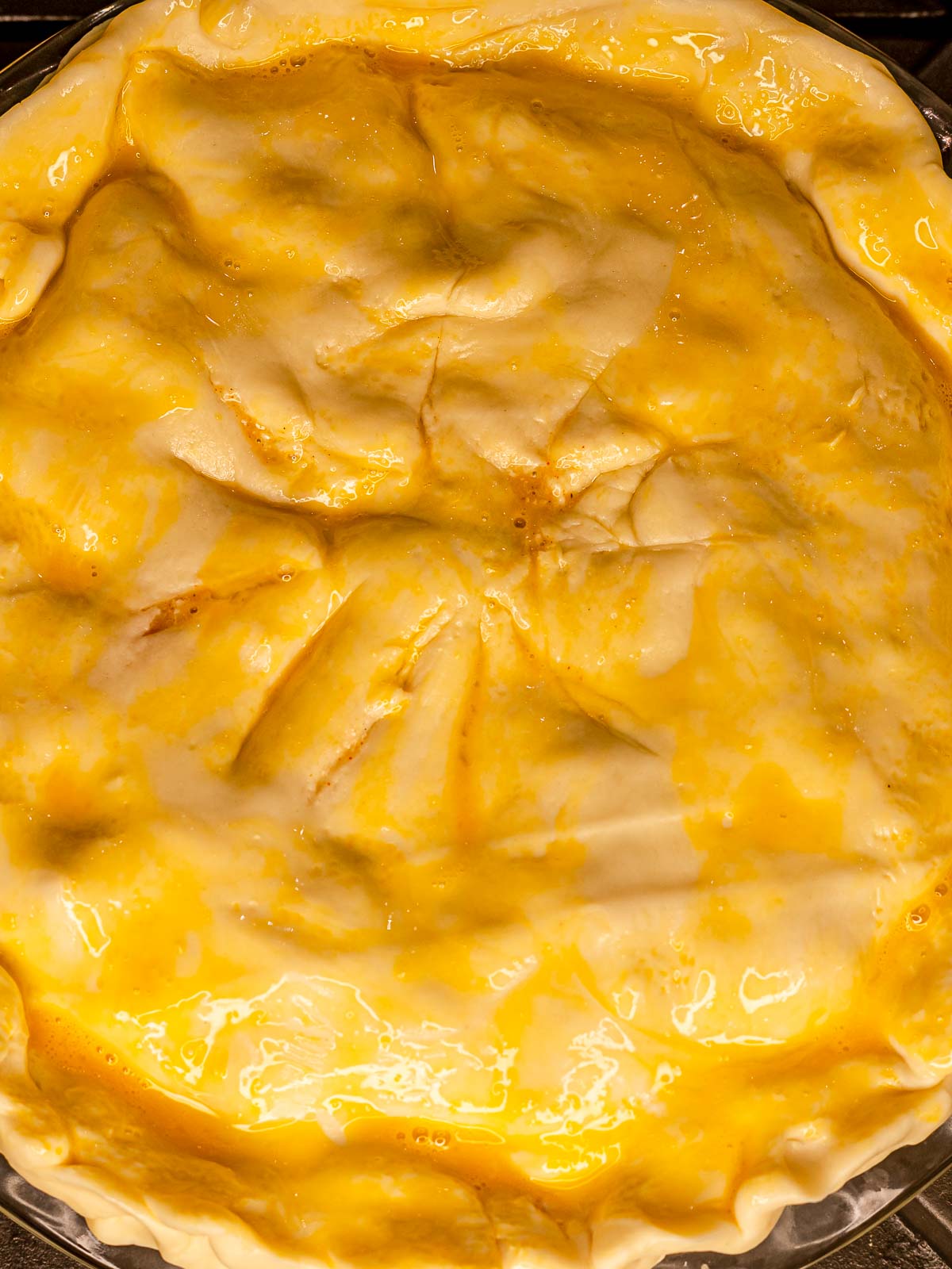 Unbaked pie with top crust brushed with egg wash.