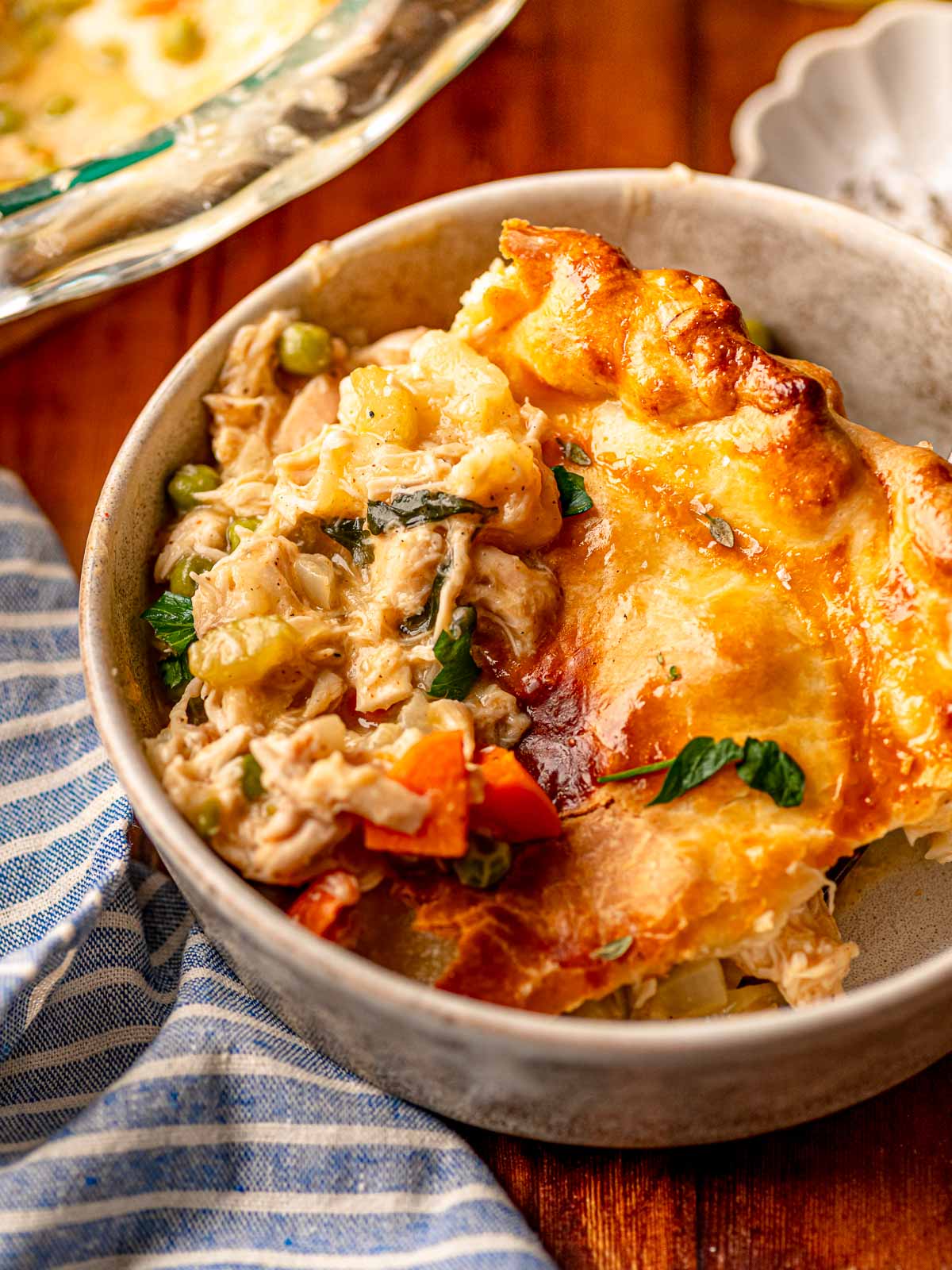 Close-up of a bowl of chicken pot pie with flaky crust and vegetables.