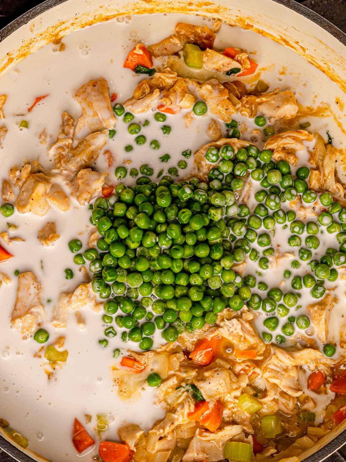 Peas and cream added to the chicken filling in the pot.