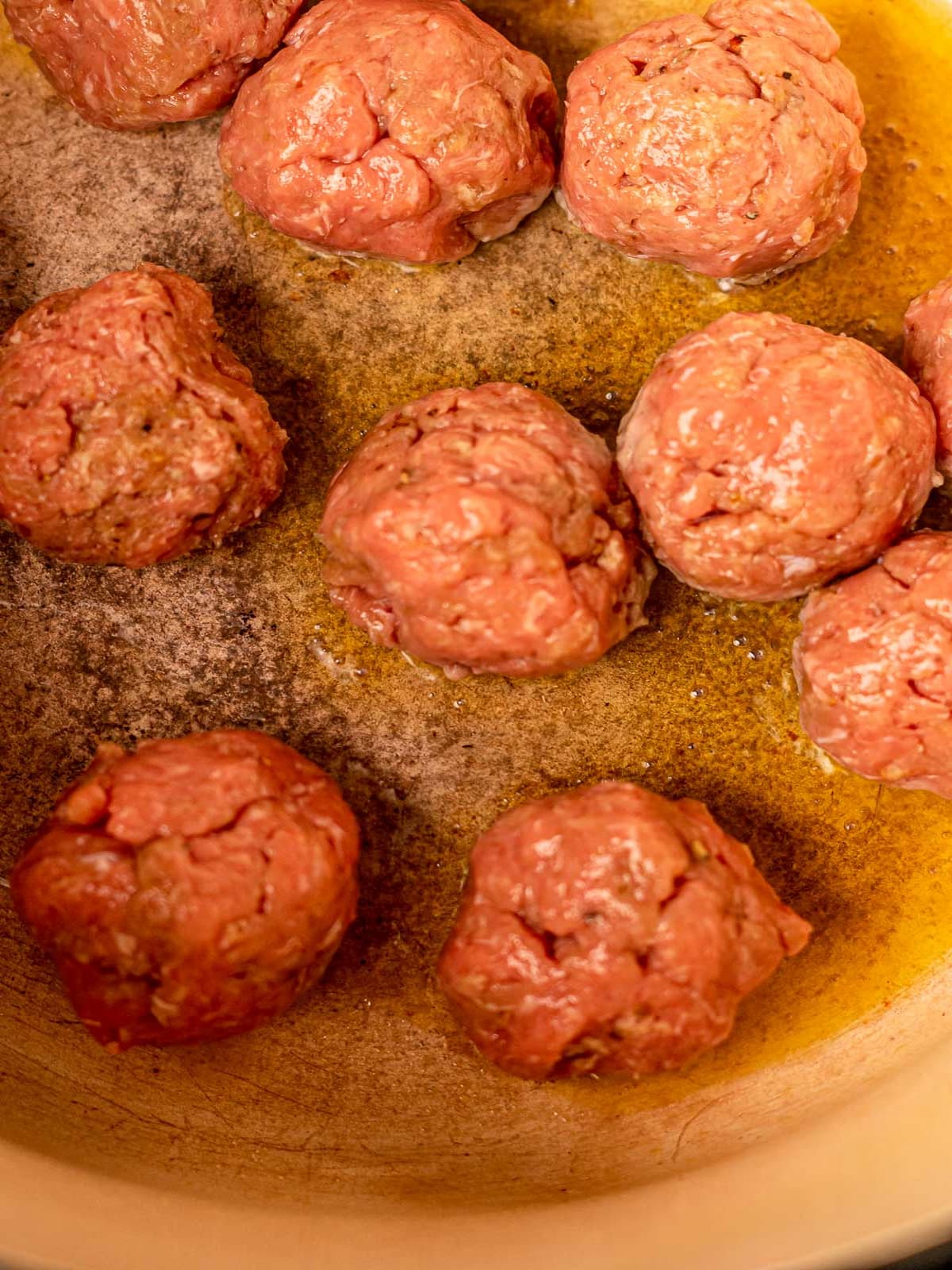 Meatballs browning in a pot.
