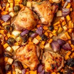 Baked chicken and vegetables on a sheet pan with golden, caramelized edges.