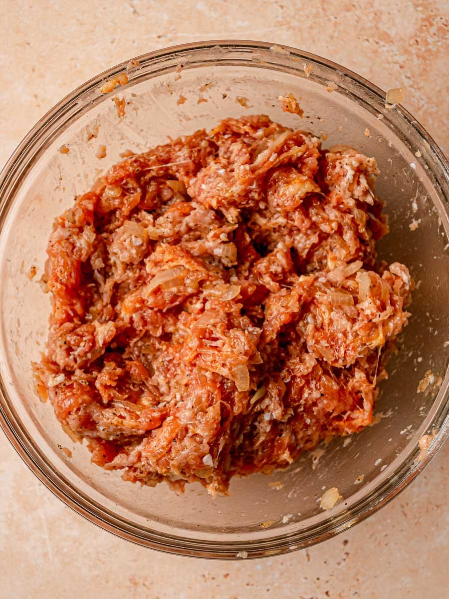 Chicken sausage roll filling mixed together in a glass bowl.