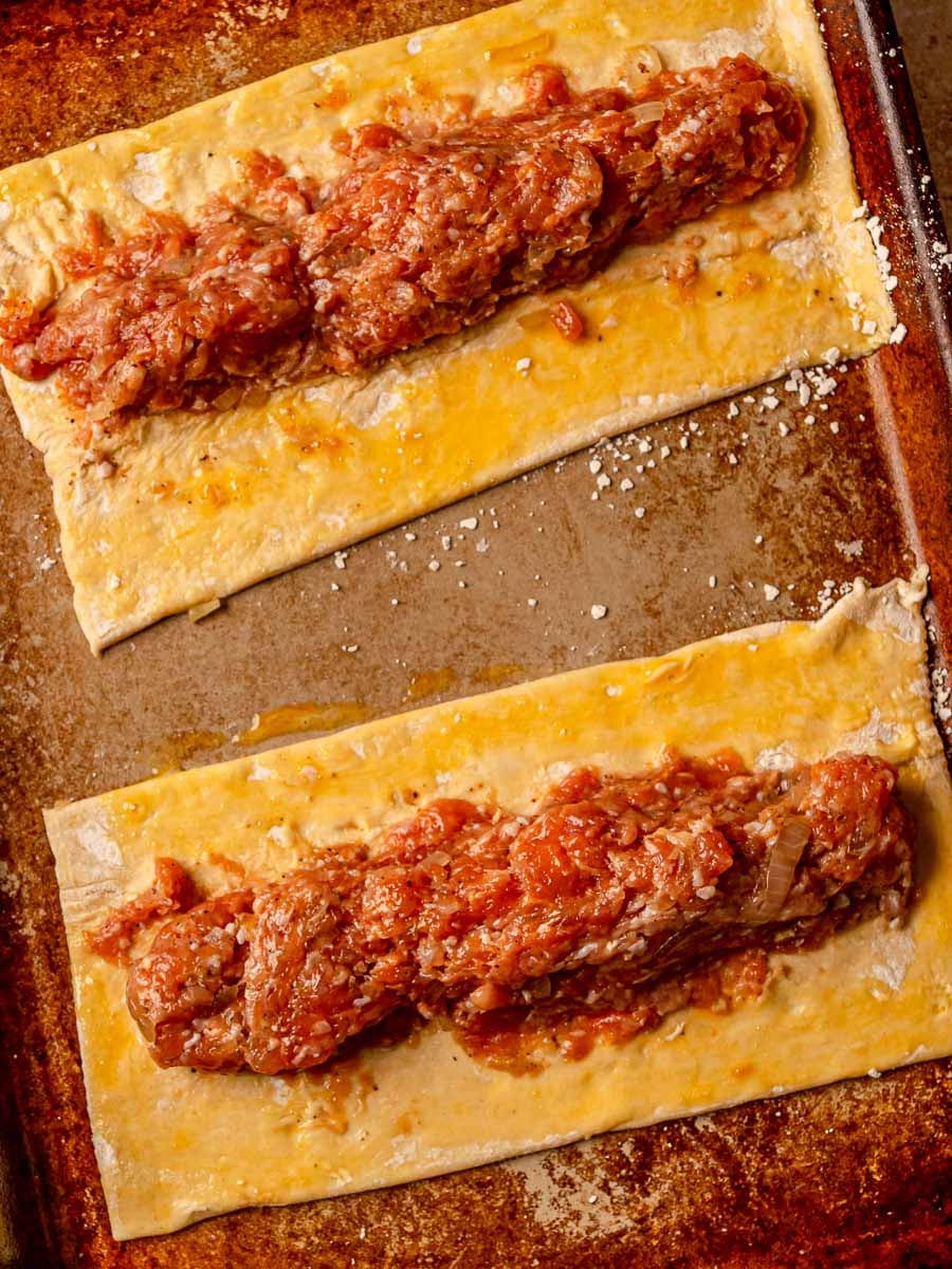 Unbaked chicken sausage filling arranged on puff pastry rectangles brushed with egg wash.