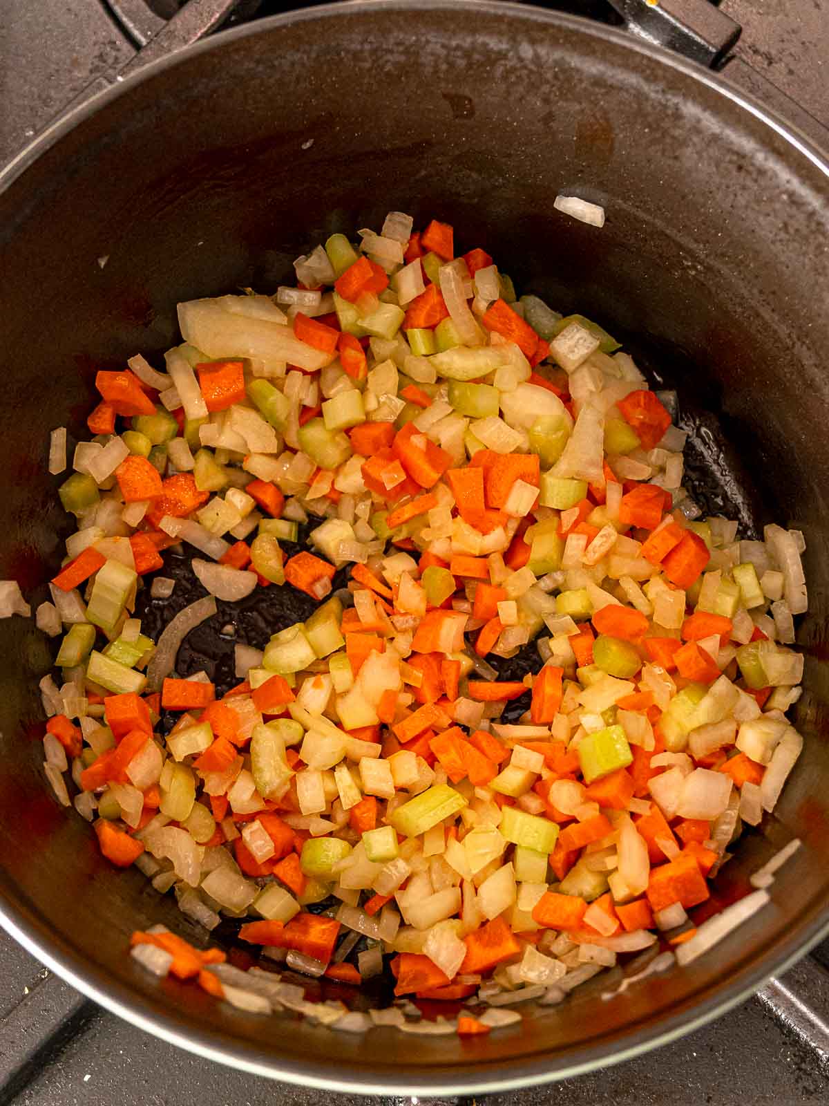 Pot filled with sautéed diced carrots, celery, and onions.