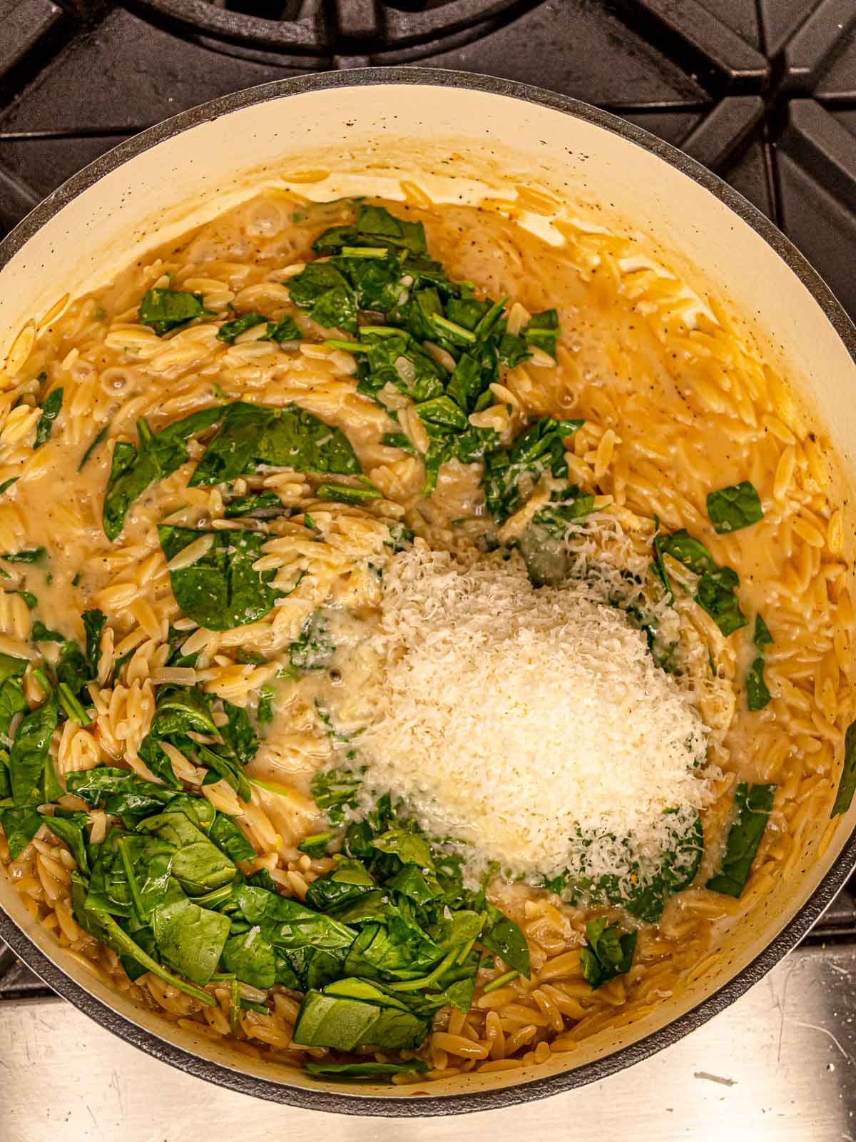 Fresh spinach and grated parmesan melting into creamy orzo.