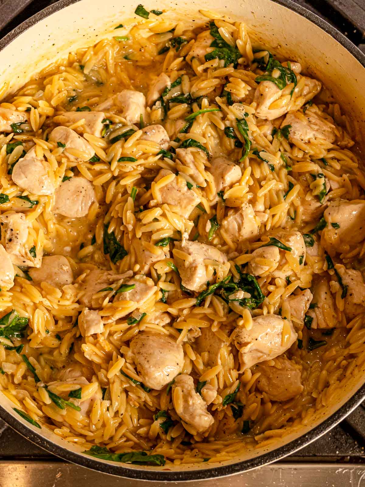 Creamy chicken orzo mixed with cooked chicken pieces and spinach.