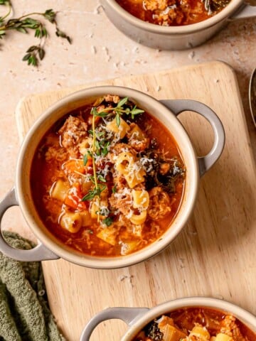 Cowl of Italian sausage kale soup filled with ditalini pasta, wilted kale, sausage, and shaved Parmesan.