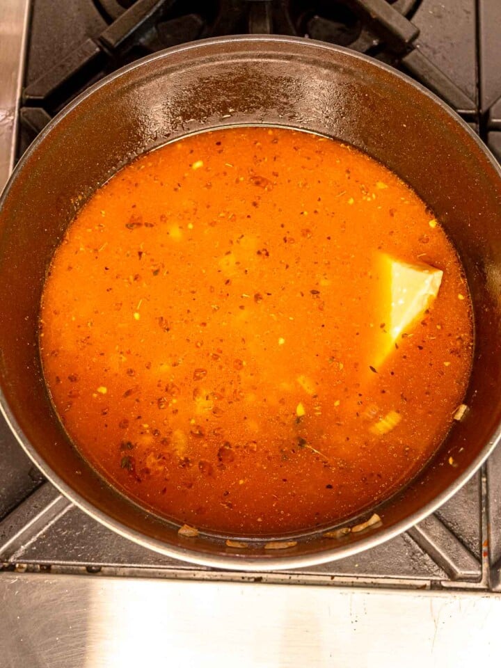 Rich tomato broth simmering with sausage, herbs, and aromatics.