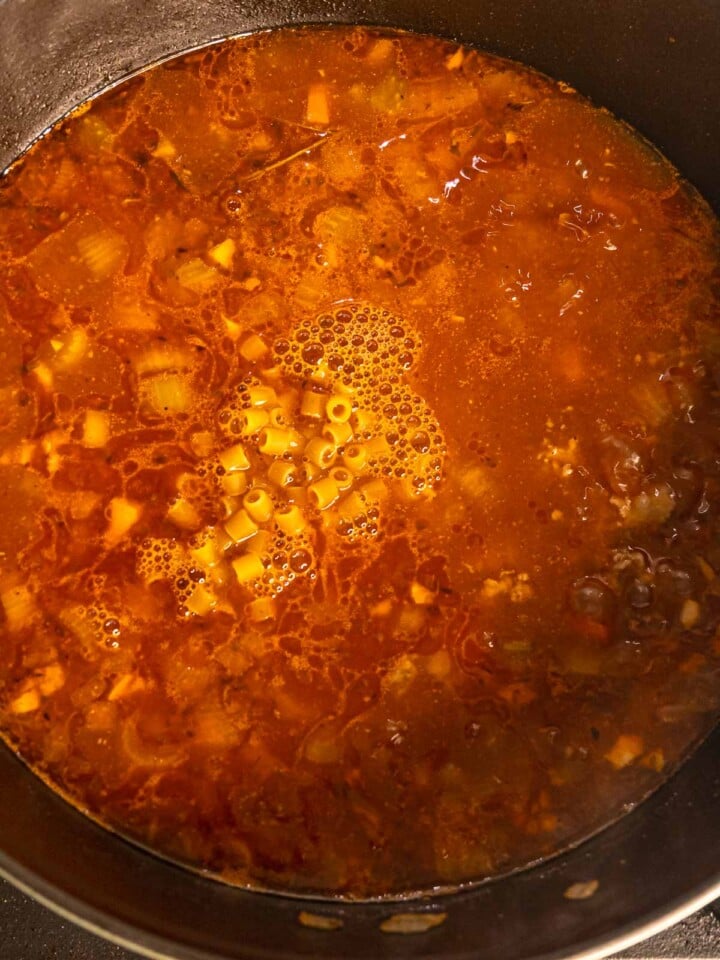 Ditalini pasta cooking in the pot of Italian sausage soup.